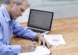 Person sitting at table, writing in notepad